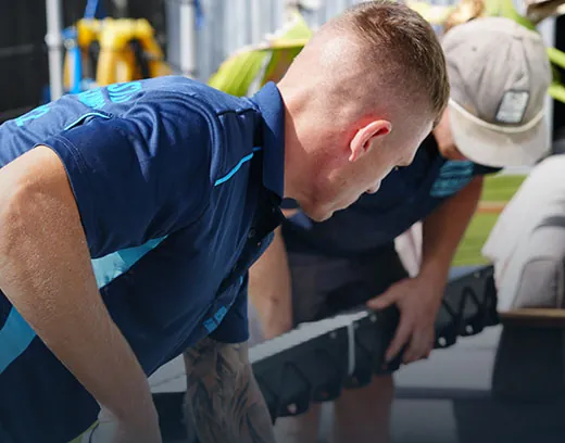 Two plumbers lifting a pipe section on site